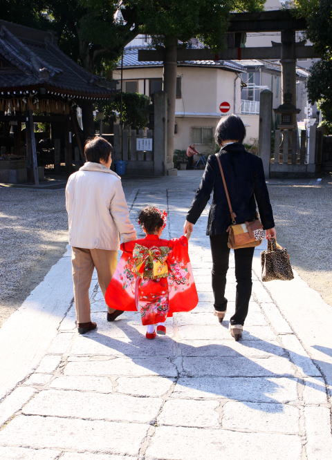 晴れ着の女の子が家族と参道を歩く後ろ姿